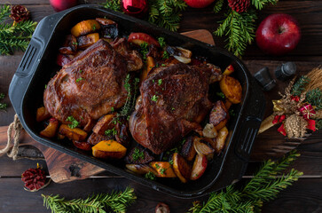 Christmas meat dish with roasted turkey shank and vegetables on wooden table