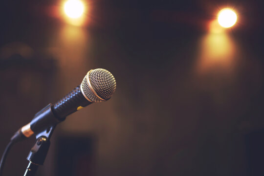 Close up of microphone on stage lighting at concert hall or conference room. copy space banner. soft focus.