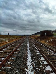 two railway tracks run side by side in winter with snow and cloudy sky (always along the railway line)
