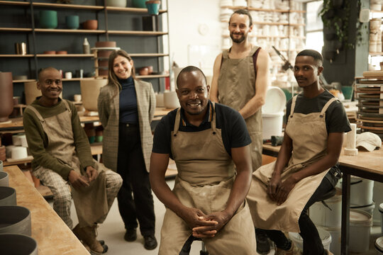 Smiling group of diverse ceramists working in a pottery studio