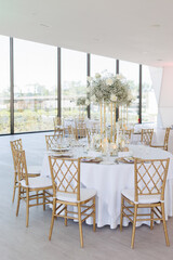 Served wedding tables with golden plates, decorative fresh  white roses and gypsophila flowers and different candles. Celebration details. Wedding decoration and decor, floristic concept	
