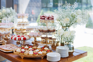 Delicious wedding reception candy bar. Tiramisu, cupcakes, sweetness, macaroons decorated by...