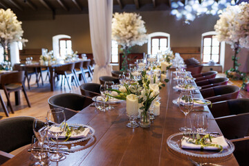 Wedding decorations. Served wedding table with decorative fresh white flowers and candles. Celebration details. 
