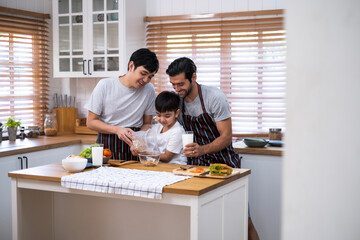 Asian father helping or teaching his son pouring cerial in glass bolw with enjoy breakfast emotion.