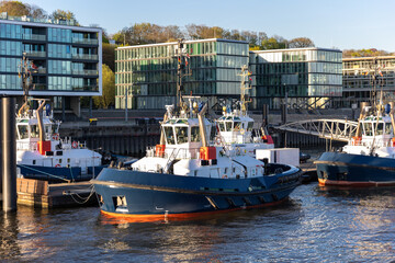 Many modern powerful tow ships service team mored in row at Hamburg Elbe harbour at evening sunset...