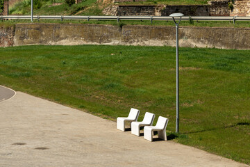 Three white bench chairs in the park.