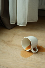 cup of coffee spilled on wooden floor 