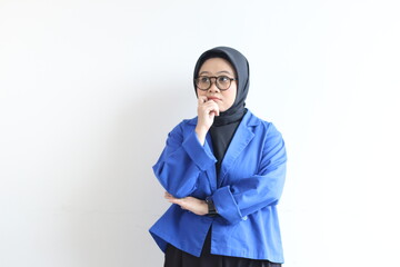 Young beautiful Asian Muslim woman, wearing glasses and blue blazer smiling looking up sideways