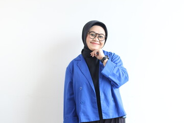 beautiful young Asian Muslim woman, wearing glasses and blue blazer with hand on chin while smiling