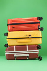 Stack of suitcase on a green background. Travel Yellow, orange color, brown suitcase on a green background. Travel and vacation concept in triples. 