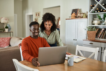 Smiling multiracial couple doing their online banking at home