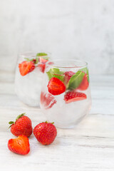 Water with strawberry, mint and lime. Ice cold summer cocktail or lemonade in glass. Detox and diet.