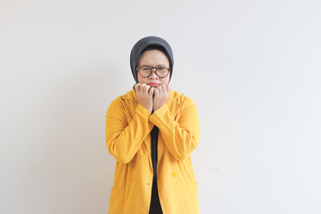 Beautiful young Asian Muslim woman, wearing glasses and yellow blazer with scared face expression