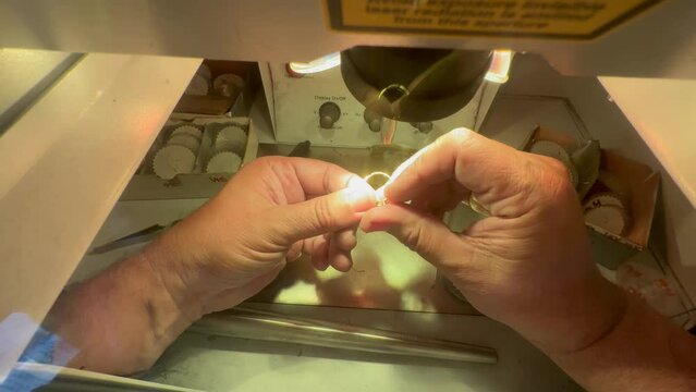 Jeweler repairing diamond ring with laser welder - closeup hands