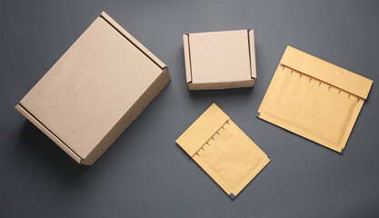 Parcel cardboard boxes and envelopes on a dark background. Top view
