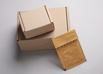 Parcel cardboard boxes and envelope on gray background.
