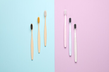 Plastic and eco bamboo toothbrushes on pastel background. Top view