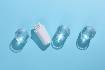 Cartridge filter for filtering water and glasses of clean water on blue background with shadow....