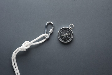 Carabiner with rope and compass on dark background. Tourism, mountaineering, outdoor activities