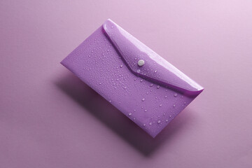 Plastic envelope with water drops on a purple background. Water protection