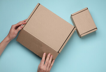 Hands open a cardboard mail box on a blue background