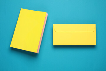 Notepad with a yellow cover and envelope floating on blue background