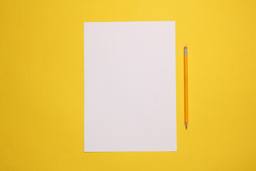 White empty sheet of paper with a pencil on a yellow background