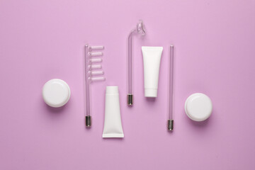 Acne treatment. Nozzles for local darsonvalization with cream jars and tubes on a purple background. Beauty concept. Flat lay