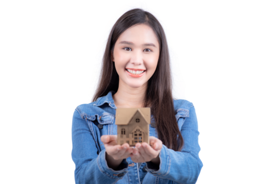 Standing sweet woman in denim shirt offering miniature house in hand. Isolated on white background