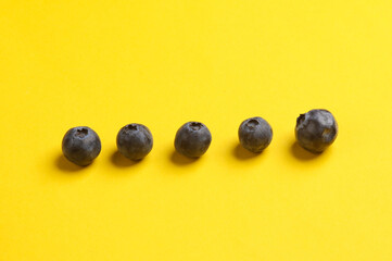 blueberries on a yellow background. Conceptual food still life