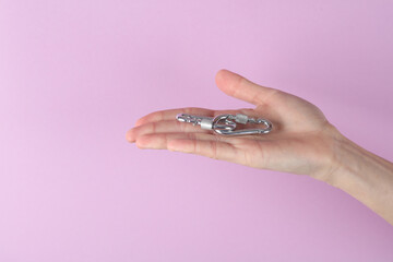 Metal carabiners on palm of the hand, purple background