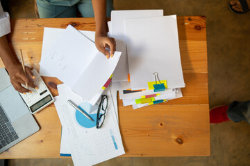 secretary searches through stacked documents on desk in office to find lease within stacked documents just before meeting. concept difficulty in finding hire purchase contract from stacked documents