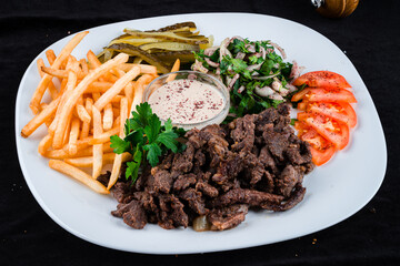 Fresh beef goulash with French fries, tomatoes, pickled cucumbers, onion and parsley salad and sauce.