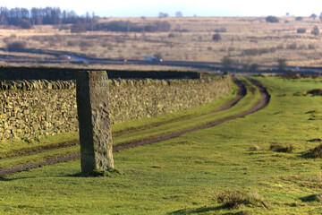 An old world stone carved street sign in old english reads'CHESTE RFIELD ROADE' (Chesterfield Road), located in the Peak District National Park.
