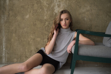 Naklejka premium Young fashion woman posing near grey wall