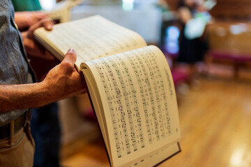 A person holds a book of shape note songs in a church