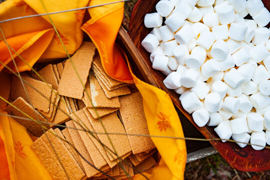 A pan of marshmallows and a sack of graham crackers sit on a table during a country wedding