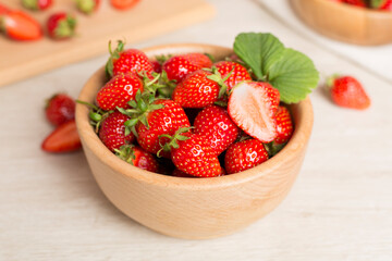 Fresh strawberries in bowl on wooden table