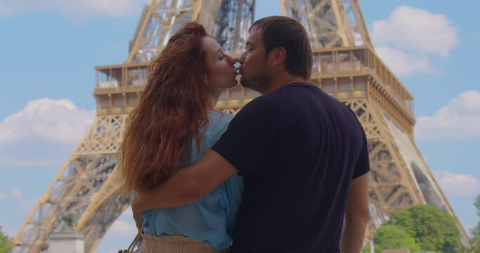 Happy beautiful couple in love visiting Paris. Man and woman on vacation in the french capital city, walking and doing activities around the eiffel tower. Eiffel Tower is most photographed landmark