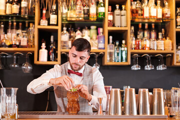 Barman lovingly preparing a cocktail for his clients. Concept: lifestyle, nightlife, drinks.