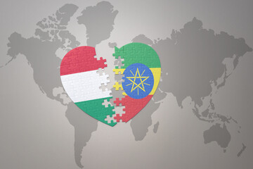puzzle heart with the national flag of ethiopia and hungary on a world map background.Concept.