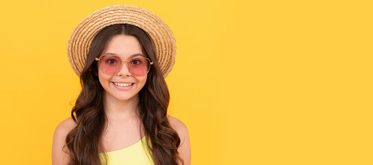 happy teen girl in summer straw hat and glasses has curly hair on yellow background, portrait. Child face, horizontal poster, teenager girl isolated portrait, banner with copy space.