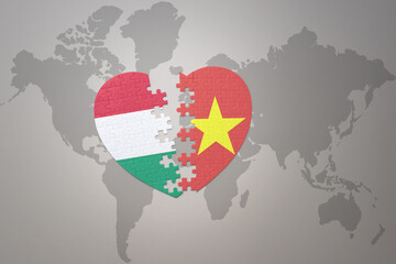 puzzle heart with the national flag of vietnam and hungary on a world map background.Concept.