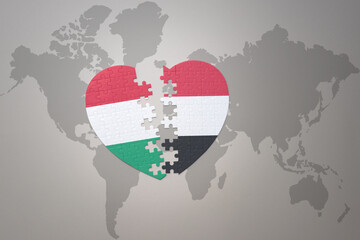 puzzle heart with the national flag of yemen and hungary on a world map background.Concept.