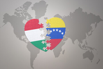 puzzle heart with the national flag of venezuela and hungary on a world map background.Concept.