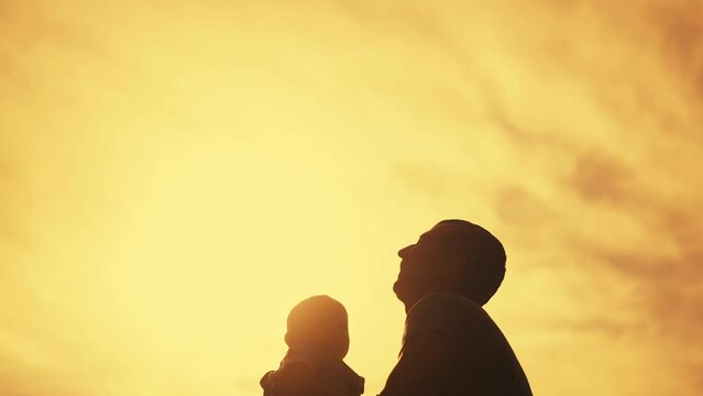 happy family. silhouette father throws his son into the air in the park at sunset. happy family kid dream concept. father plays with his son in the park throws up. family lifestyle father and son