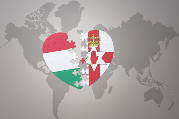 puzzle heart with the national flag of northern ireland and hungary on a world map background.Concept.