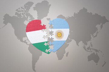 puzzle heart with the national flag of argentina and hungary on a world map background.Concept.