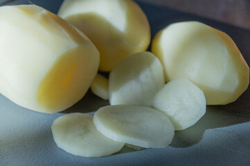 Fresh raw peeled and sliced potatoes on kitchen cutting board, close up. High quality photo