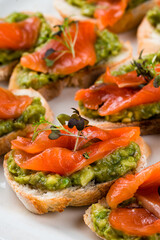 Fresh bruschetta with salmon, avocado and microgreens, closeup.
